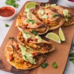 A wooden board with five Baked Chicken Tacos with Avocado Lime Crema on top.