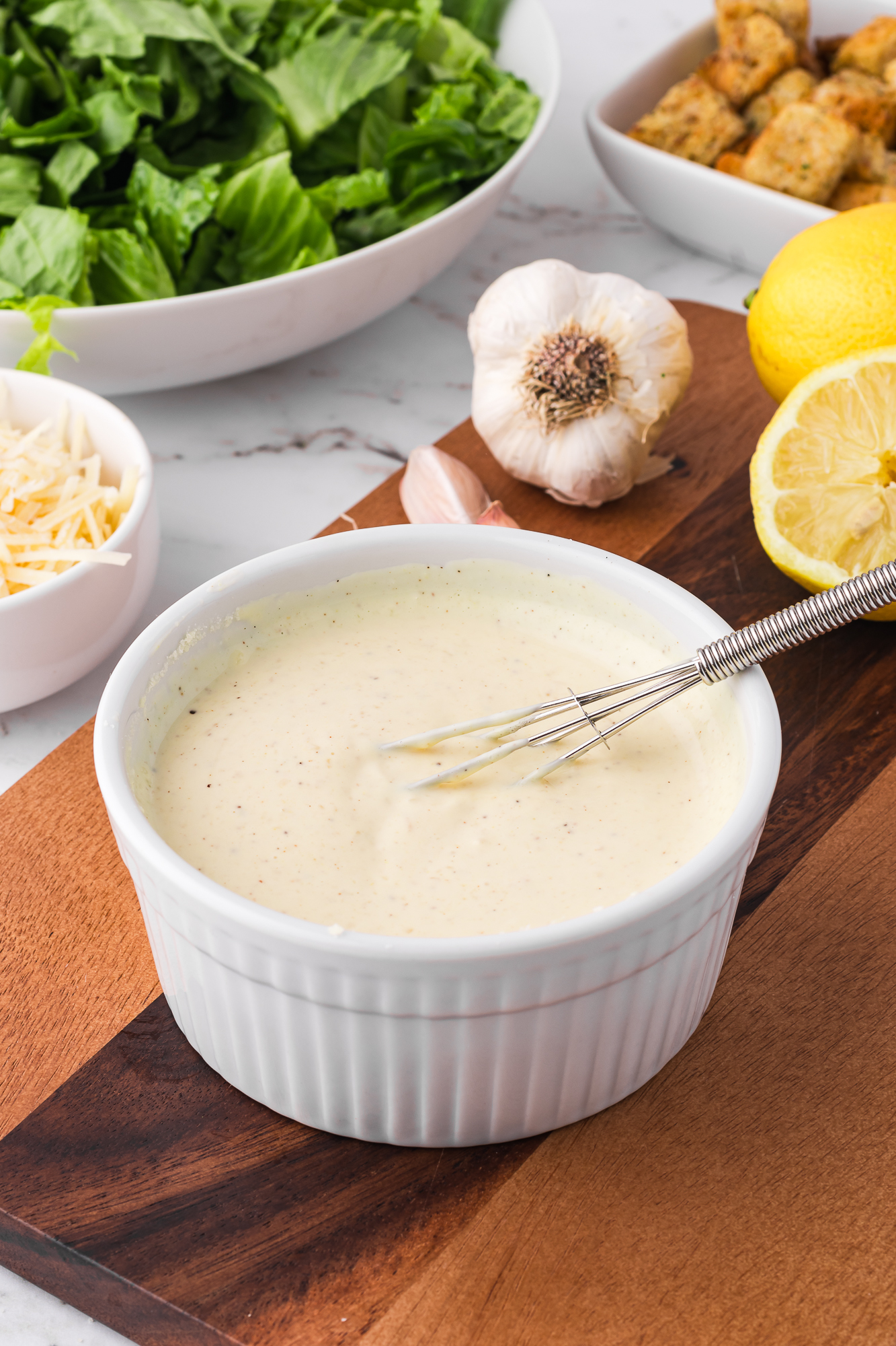 A small bowl of Homemade Caesar Dressing with a small whisk in it.