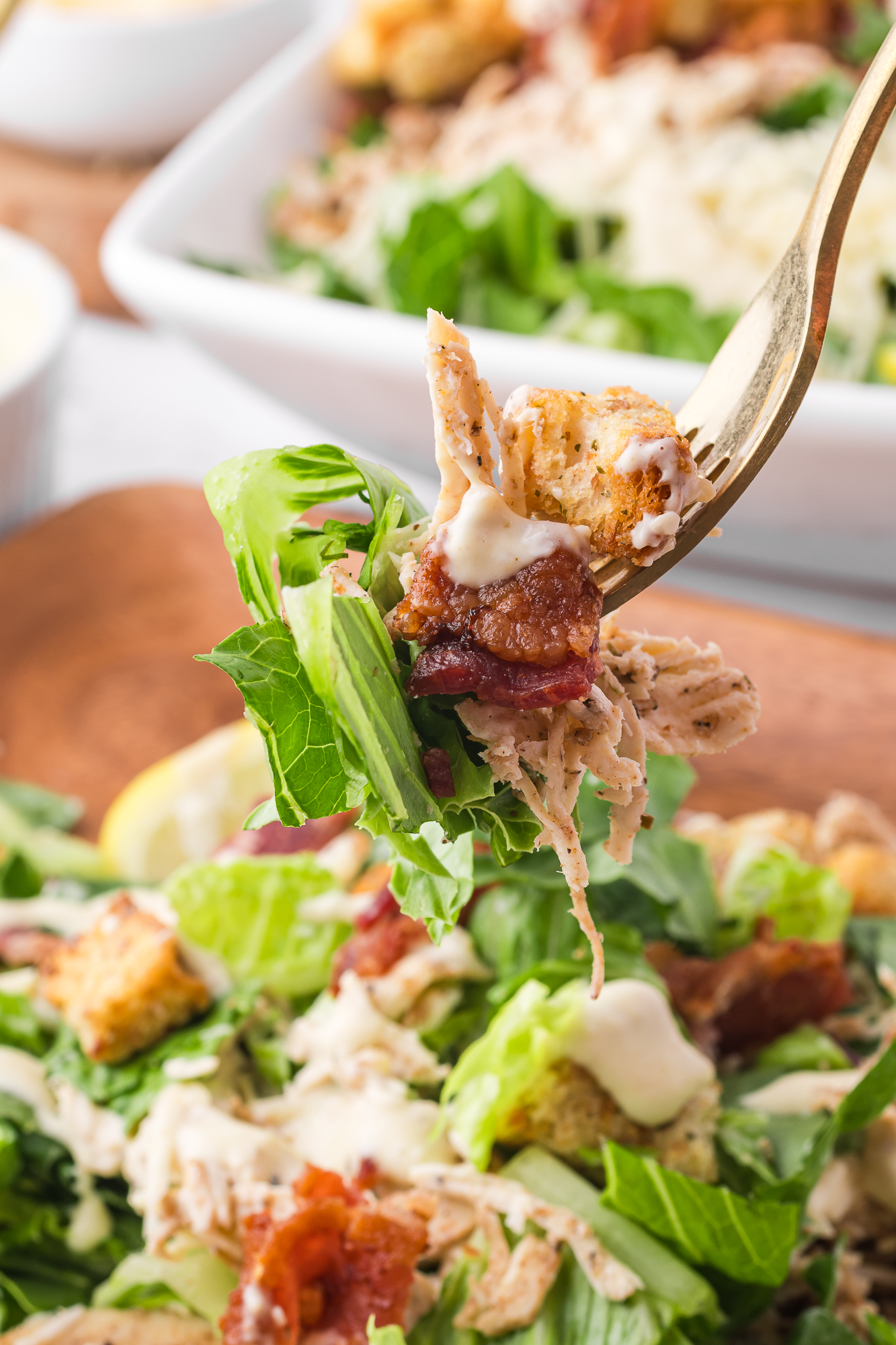 A closeup of a forkful of Chicken Bacon Caesar Salad.