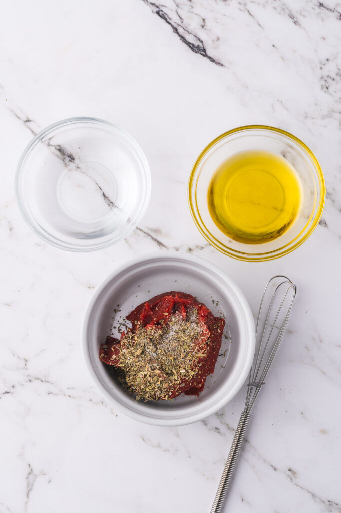 Three small bowls holding the ingredients for the tomato sauce.