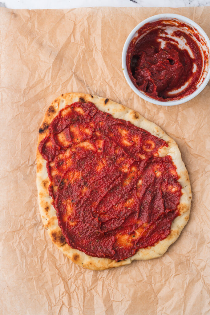 A flatbread covered with tomato sauce.