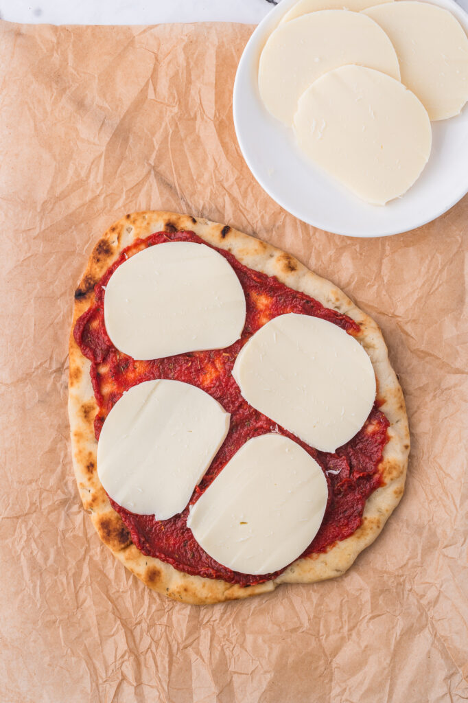 A flatbread covered with tomato sauce and mozzarella cheese.