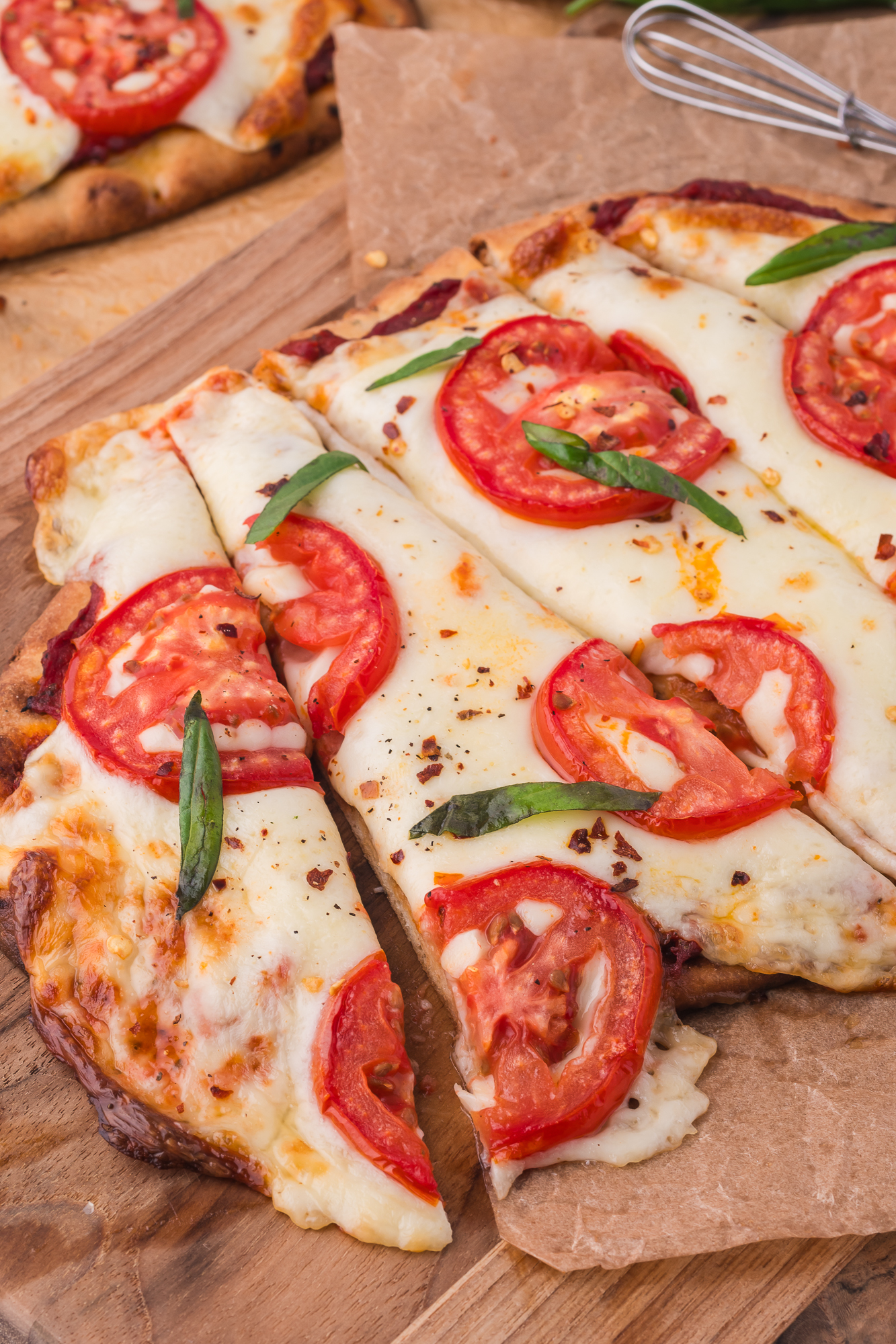 A close-up of a sliced Margherita Flatbread on a wooden cutting board.