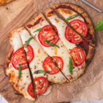 A sliced Margherita Flatbread on a wooden cutting board.