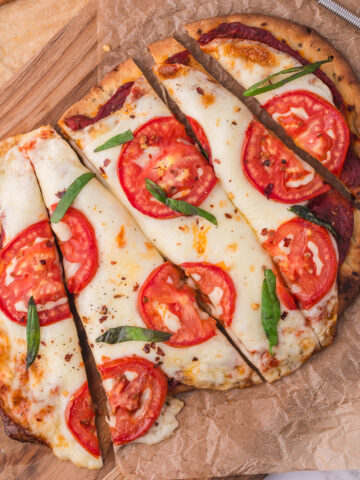 A sliced Margherita Flatbread on a wooden cutting board.