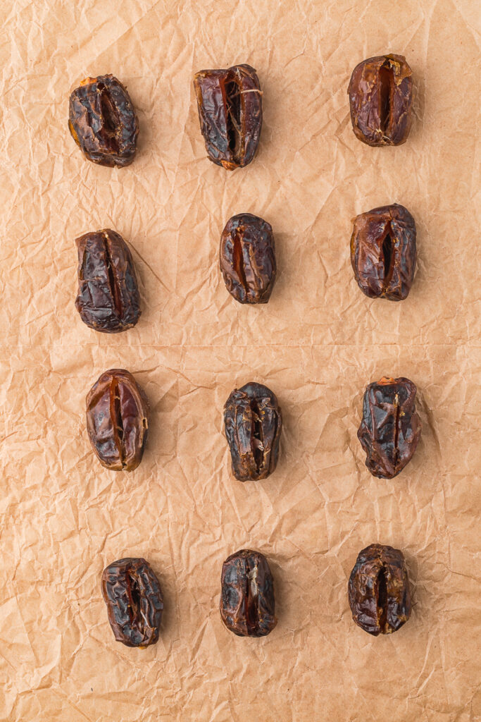 A piece of parchment paper holding 12 pitted dried dates.