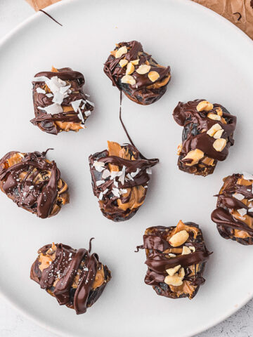 A white plate holding eight Peanut Butter Stuffed Dates.