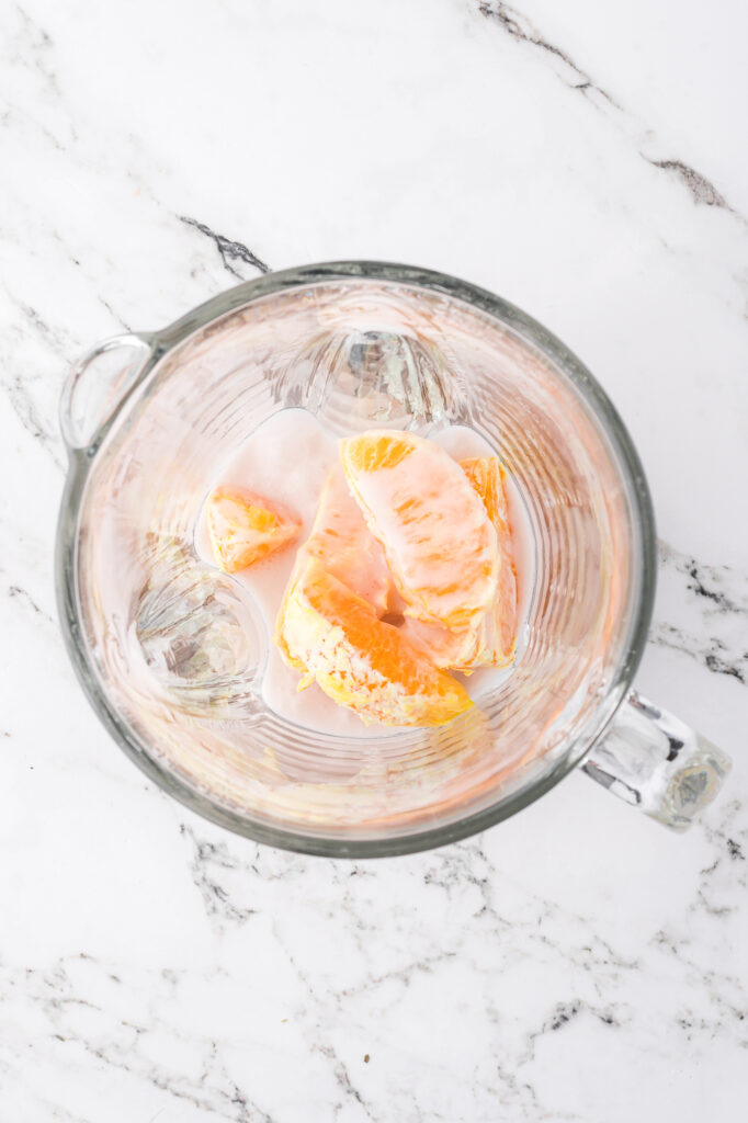 A top view of sliced oranges in a blender.