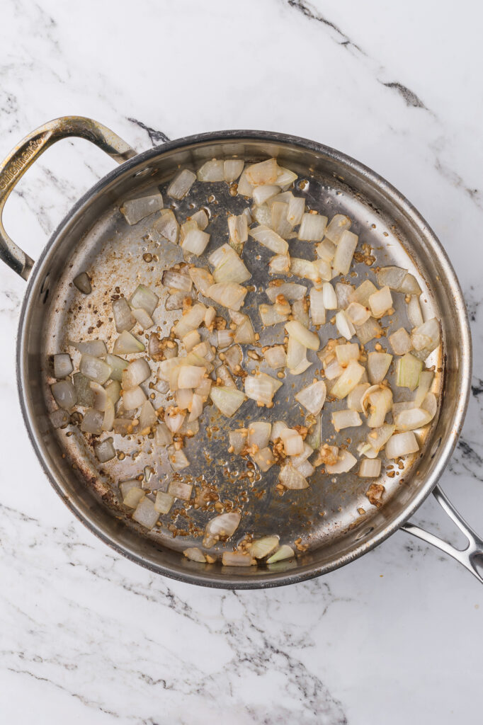 Onions getting sauteed in a pan for Shrimp Chow Mein.