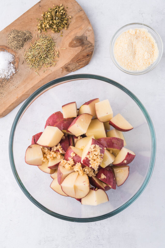 A glass bowl of cut up raw red potatoes.