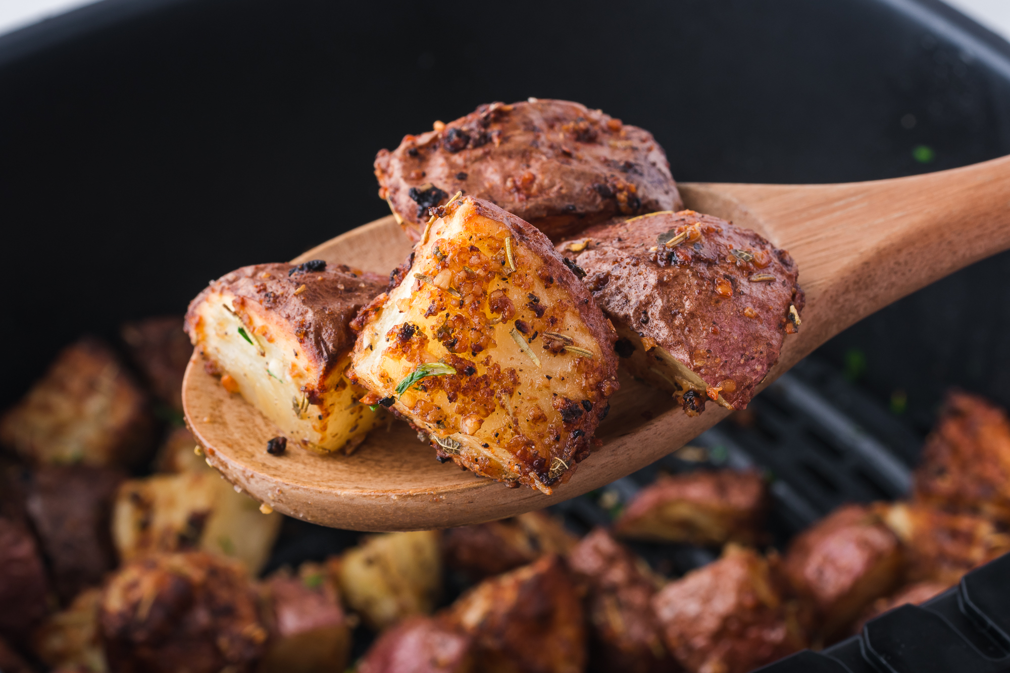 A close-up of some Air Fryer Red Potatoes on a wooden spoon.