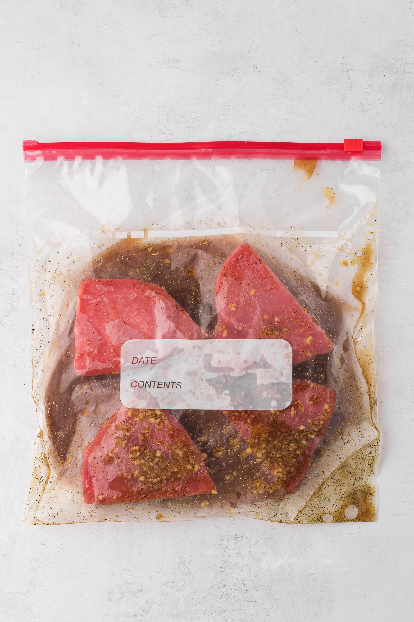 Four tuna steaks marinating in a plastic bag.