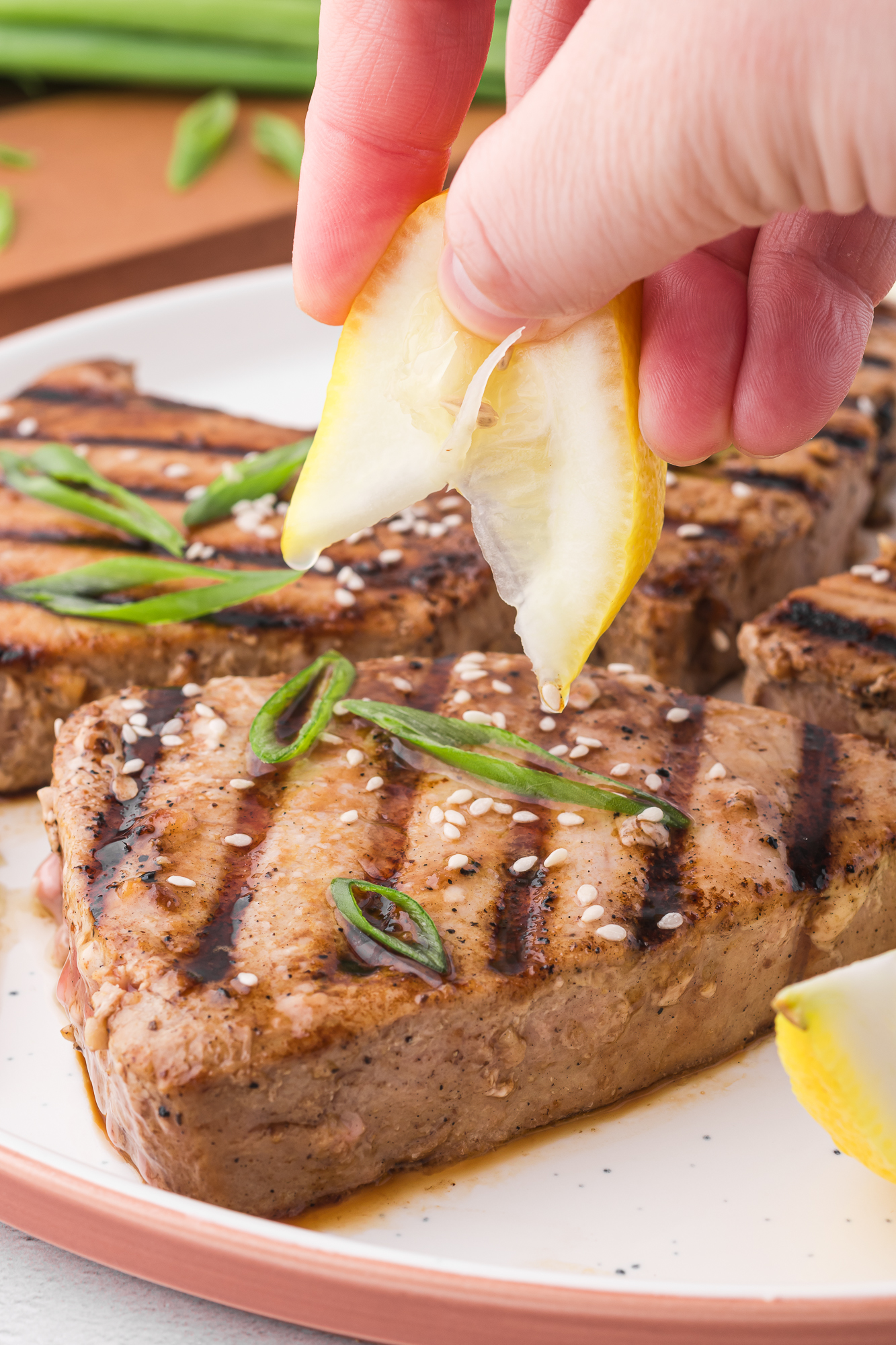 A close up of a lemon wedge being squeezed over a Grilled Tuna Steak.