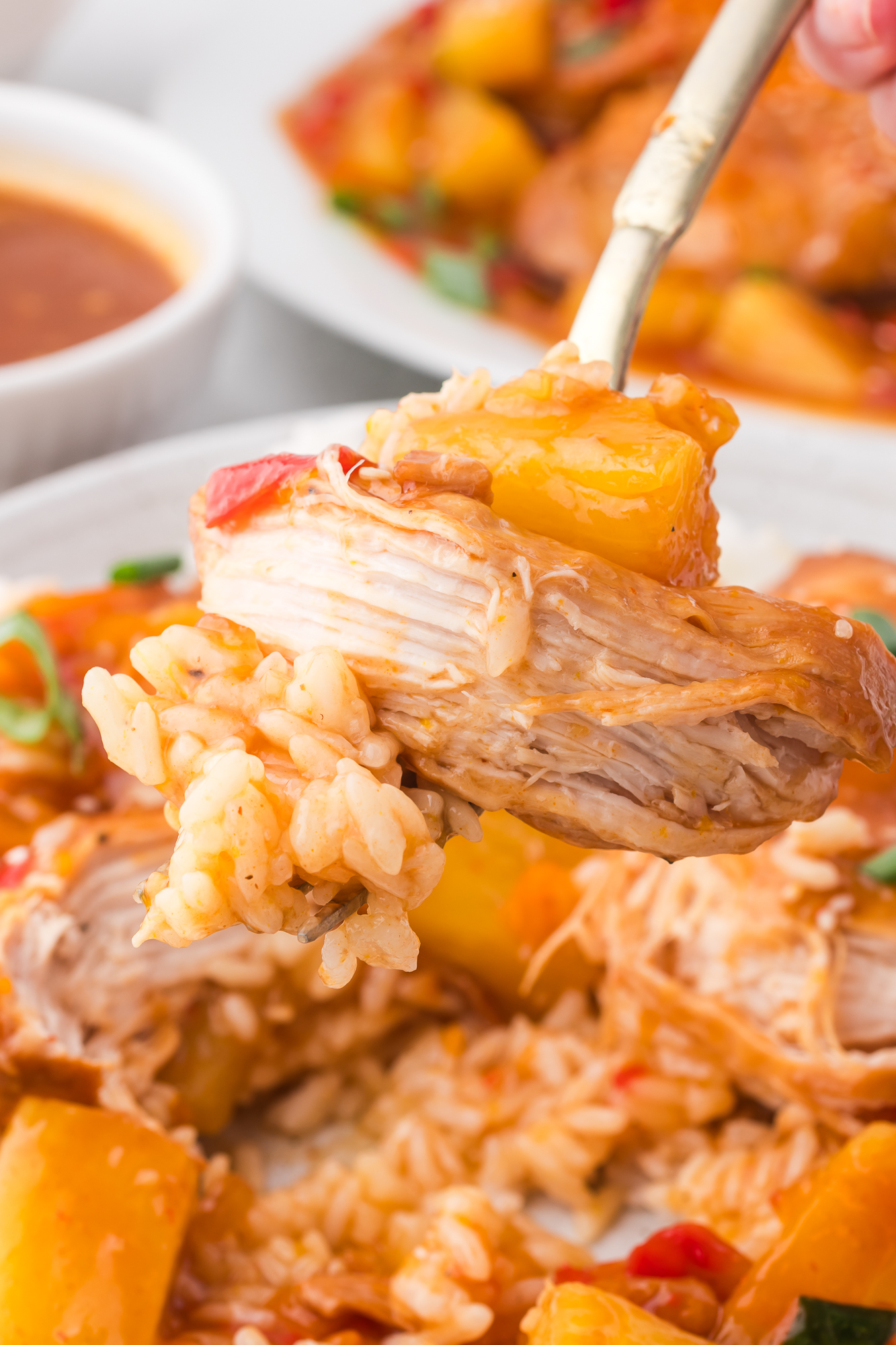 A close up of a forkful of A slow cooker of cooked Slow Cooker Hawaiian Chicken..