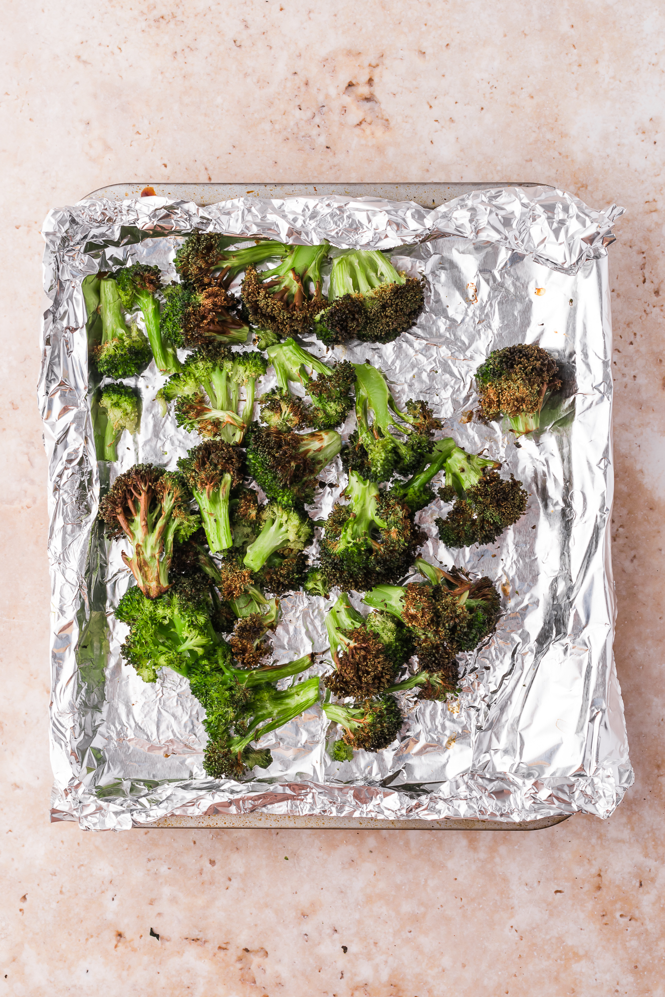 A foil-lined pan of roasted broccoli.