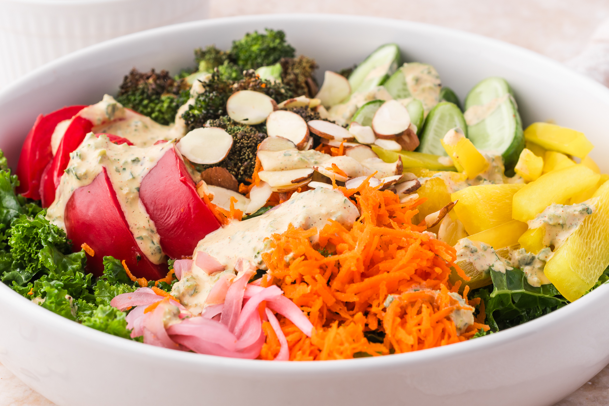 A close-up of a white bowl of Kale Broccoli Salad.