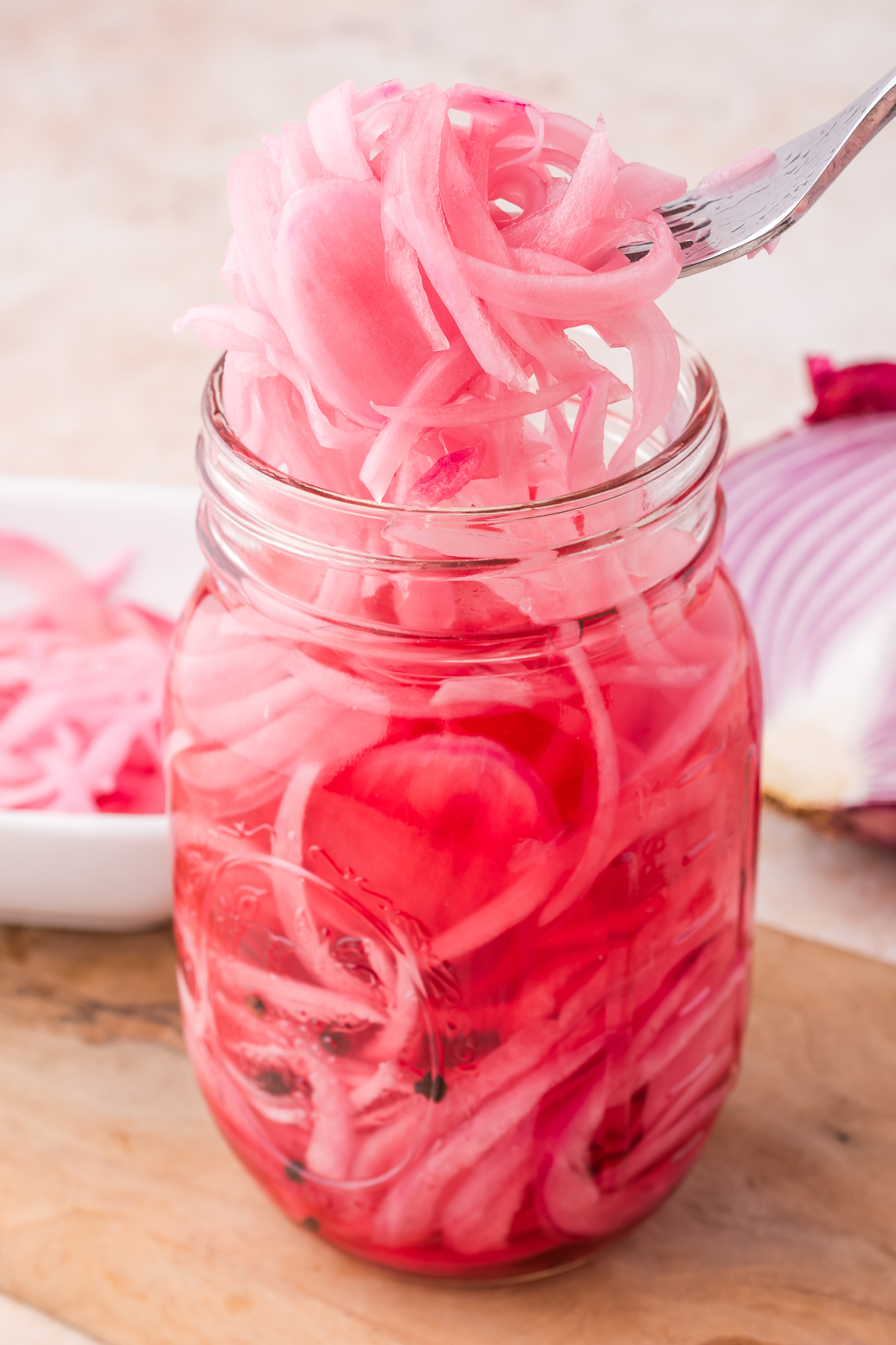 A fork removing some Pickled Red Onions from a mason jar.