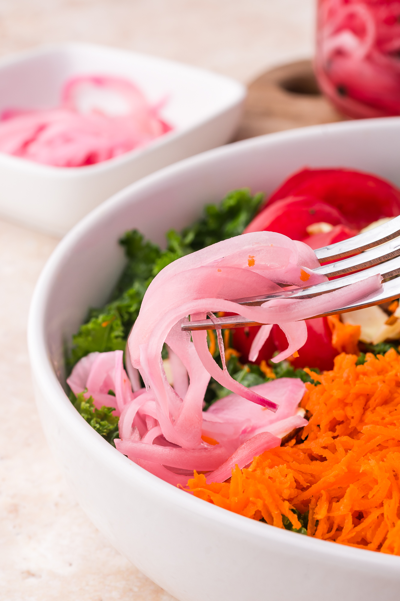 A fork holding some Pickled Red Onions above a salad.