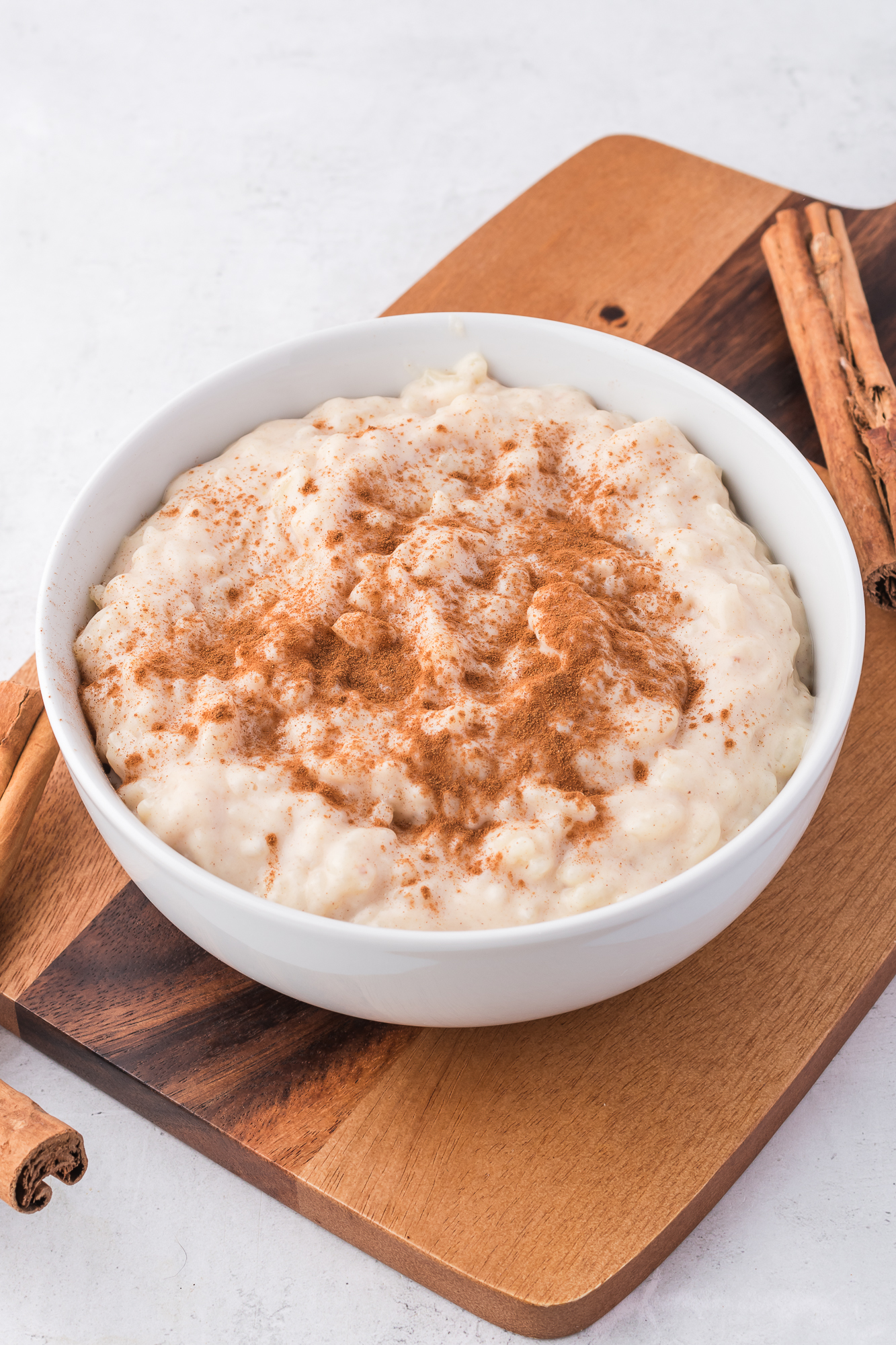 A white bowl of Rice Pudding with Condensed Milk with cinnamon sprinkled on top.