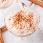 A glass bowl of Rice Pudding with Condensed Milk with cinnamon sprinkled on top.