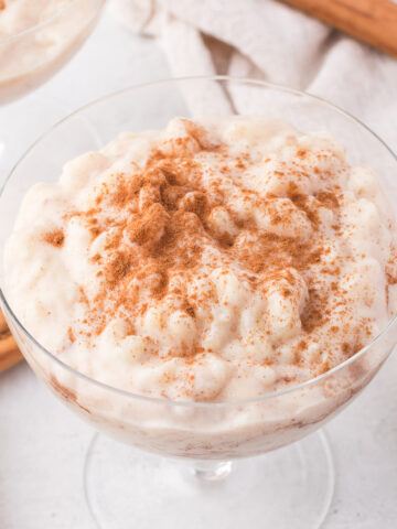 A glass bowl of Rice Pudding with Condensed Milk with cinnamon sprinkled on top.