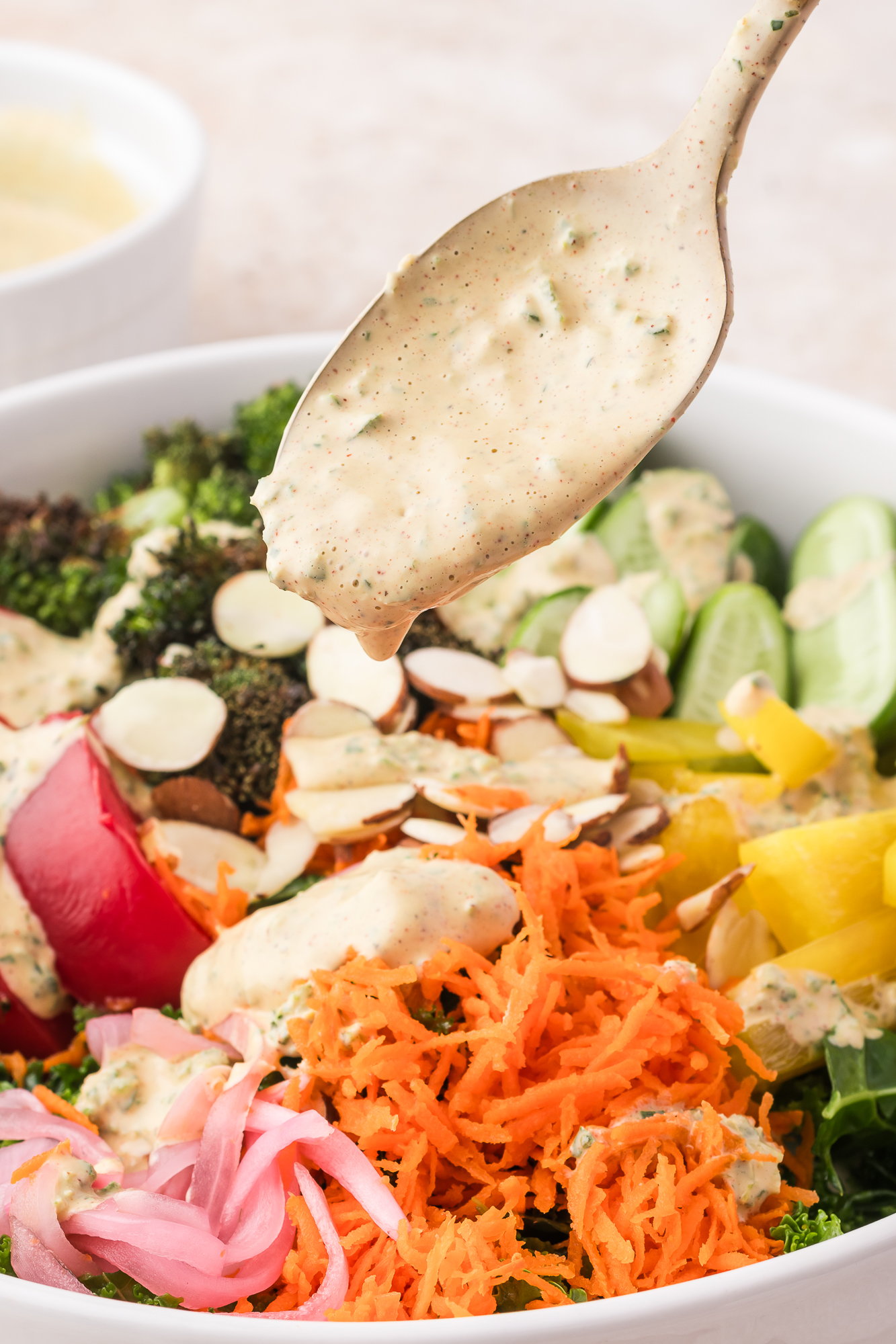 A spoon of Smoky Poblano Ranch Dressing over a vegetable medley salad.