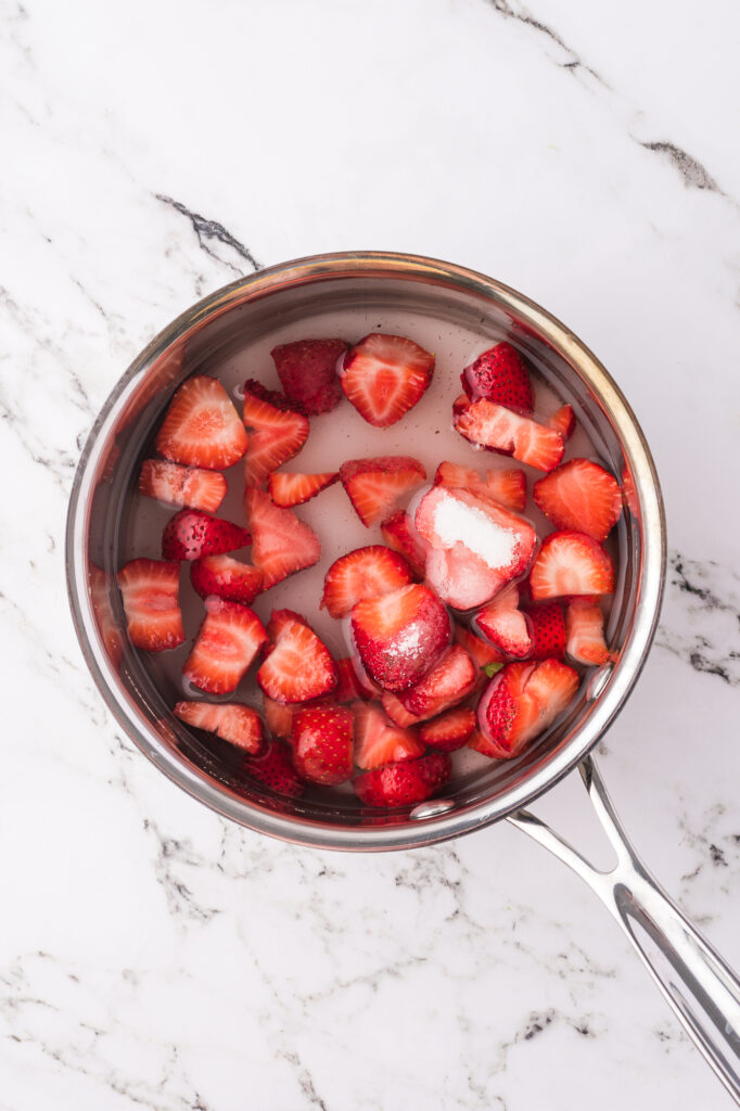 A saucepan of sliced strawberries and sugar.