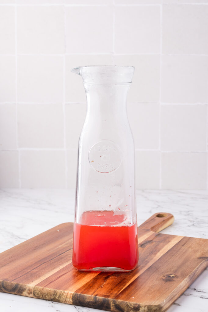 A carafe of strawberry juice mixed with lemon juice.