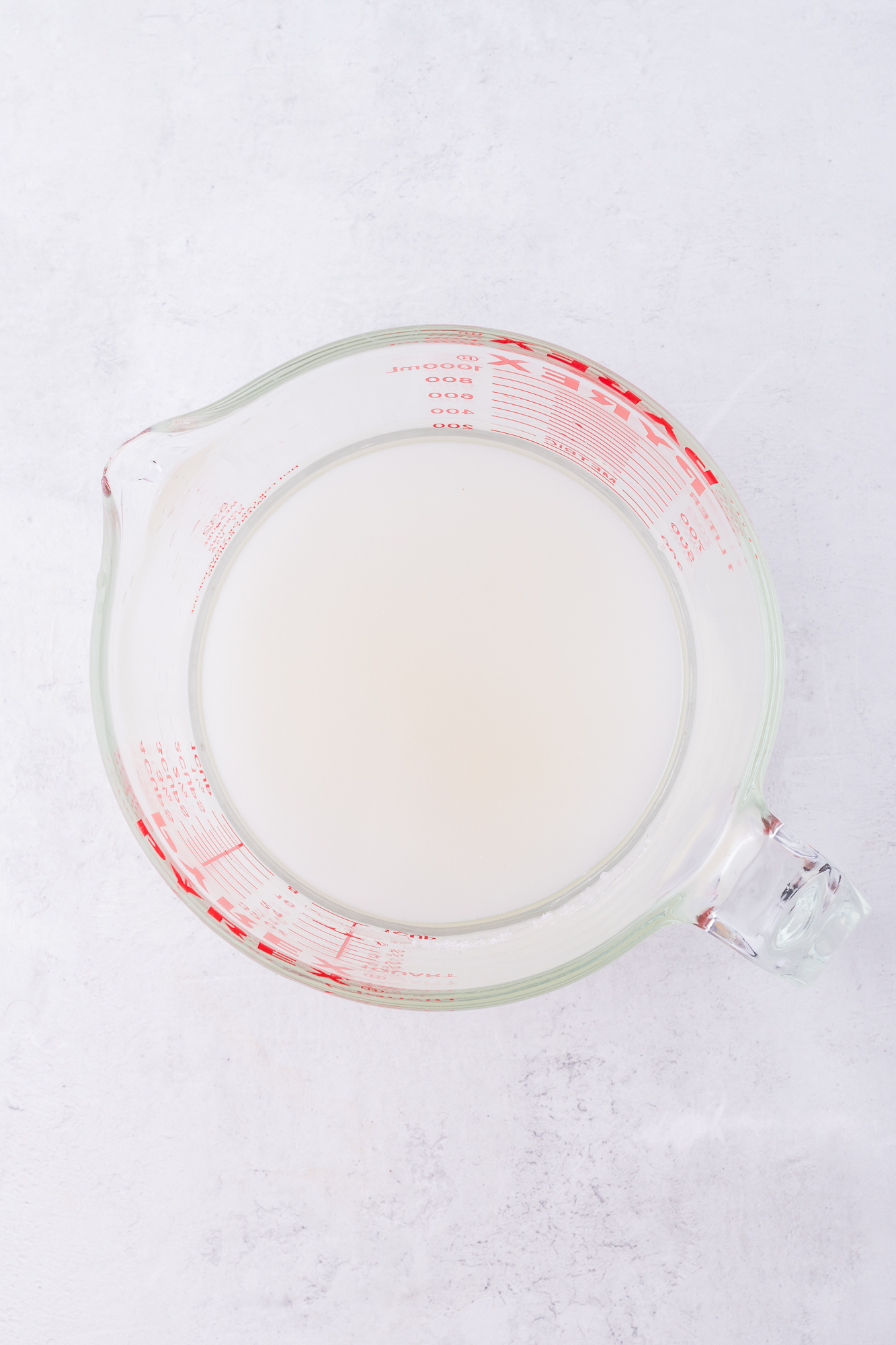 A glass measuring cup of water and sugar.