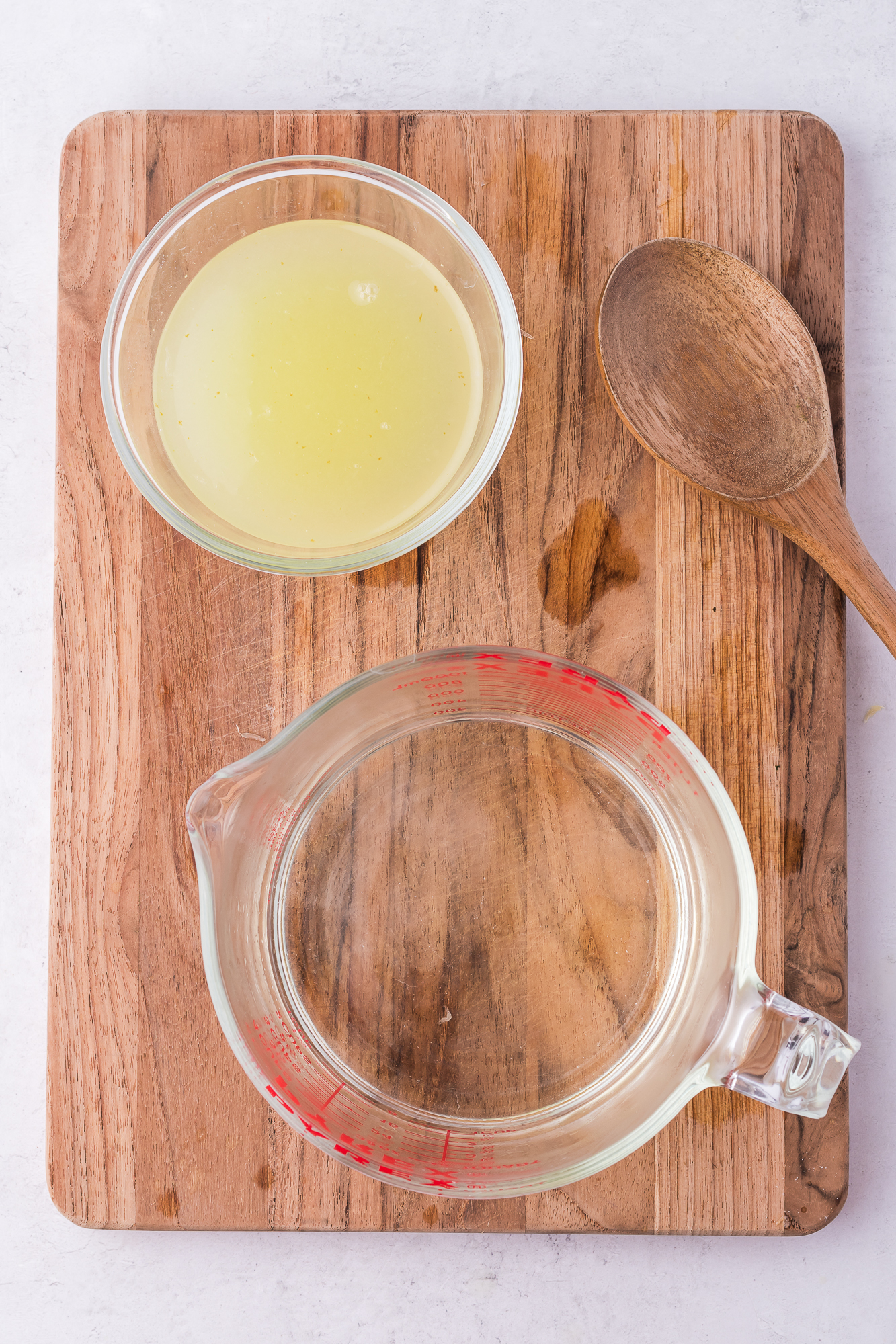 A measuring cup of simple syrup and a class of fresh squeezed lemon juice.