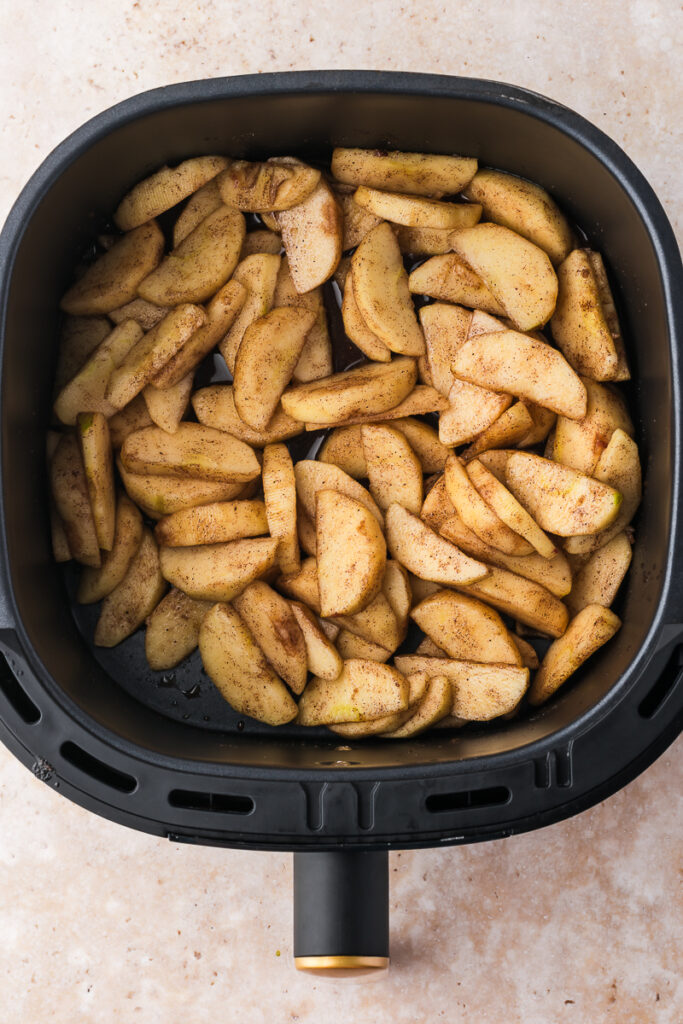 An air fryer basket with the prepared Air Fryer Apples with Bourbon.