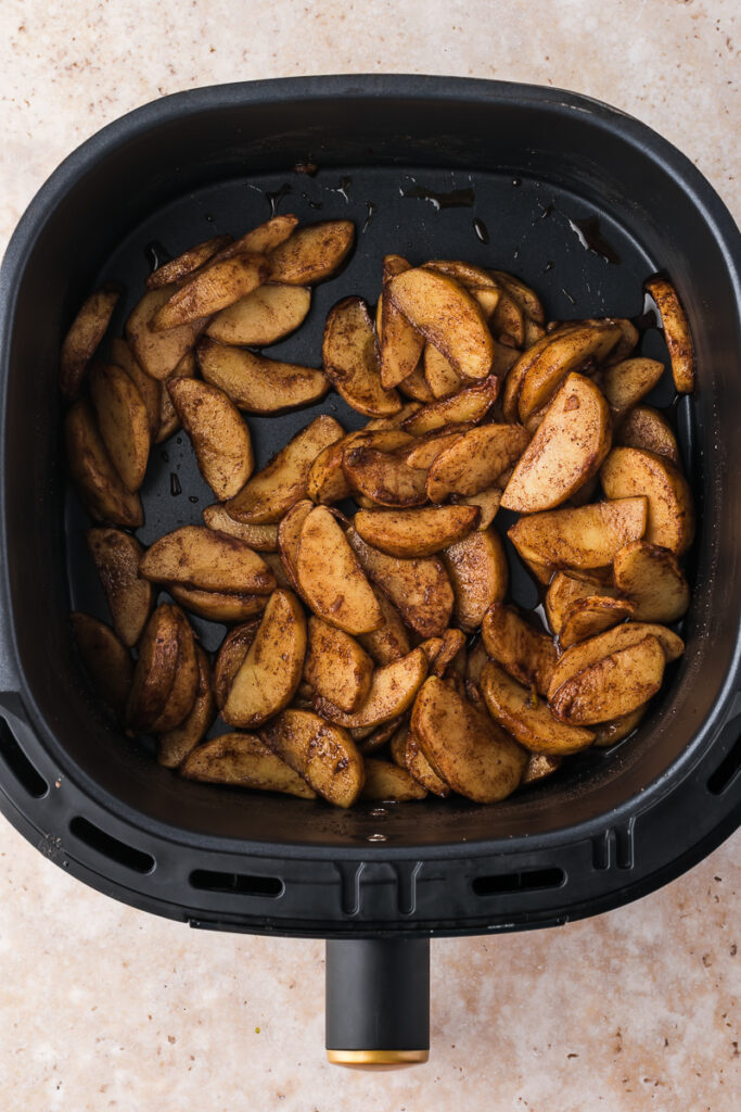 An air fryer basket with the cooked Air Fryer Apples with Bourbon.