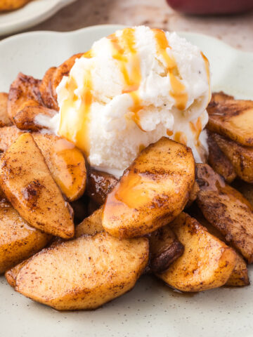 A plate of Air Fryer Apples with Bourbon topped with vanilla ice cream.