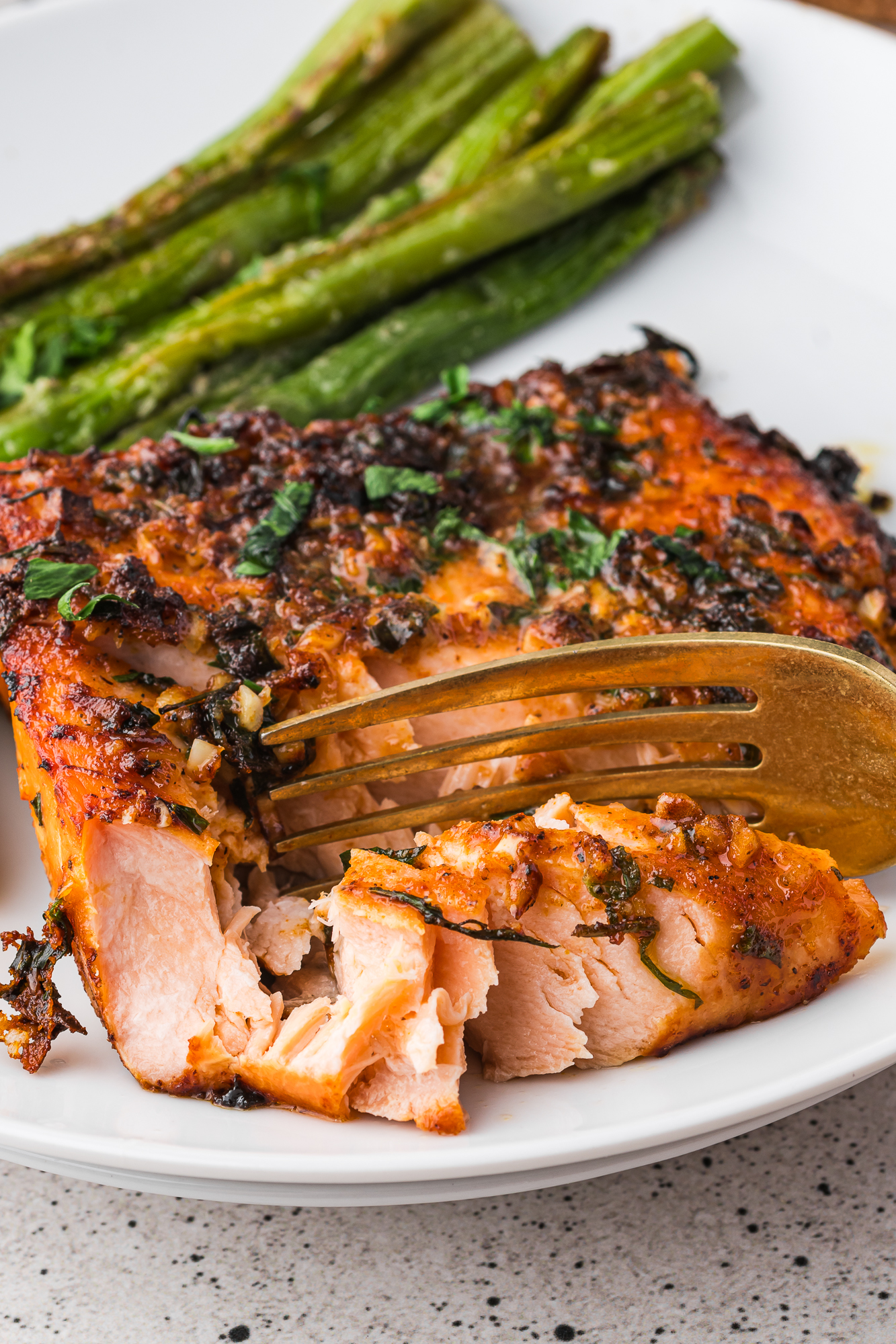 A close-up of a fork cutting into a Air Fryer Garlic Butter Salmon filet