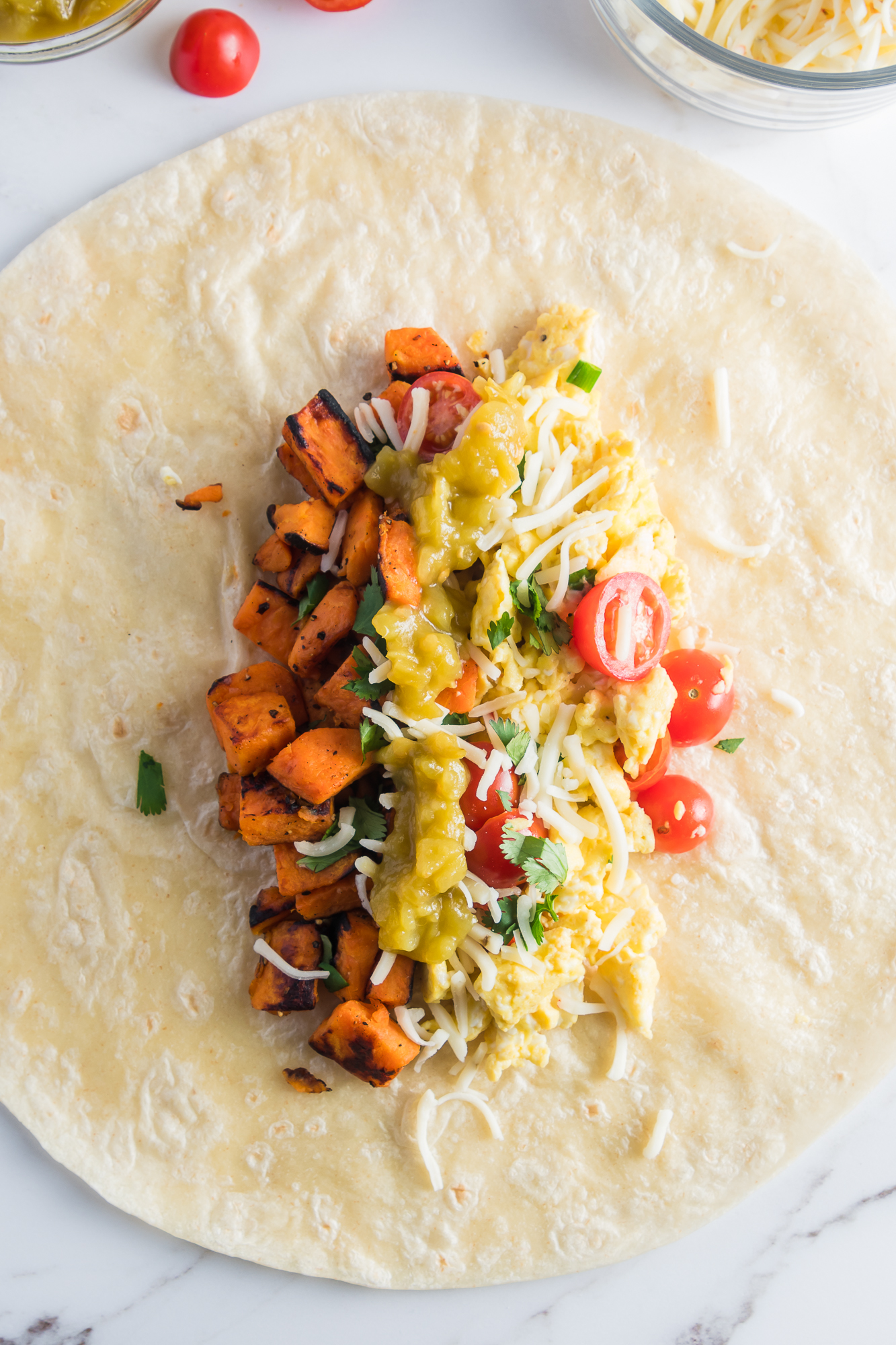 A burrito open flat top with all the fillings for Sweet Potato Breakfast Burritos.