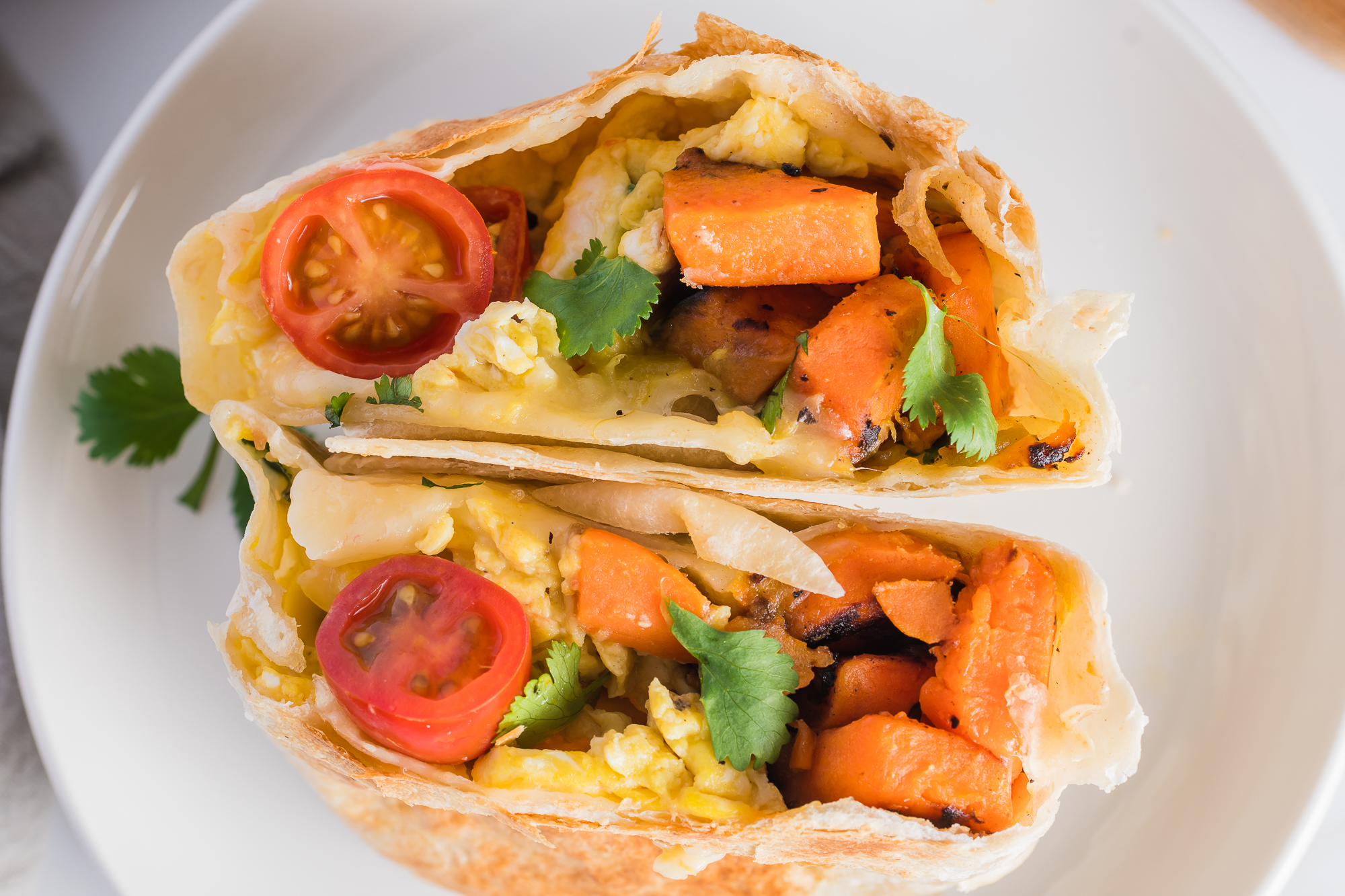 A close-up of a Sweet Potato Breakfast Burrito sliced in half.