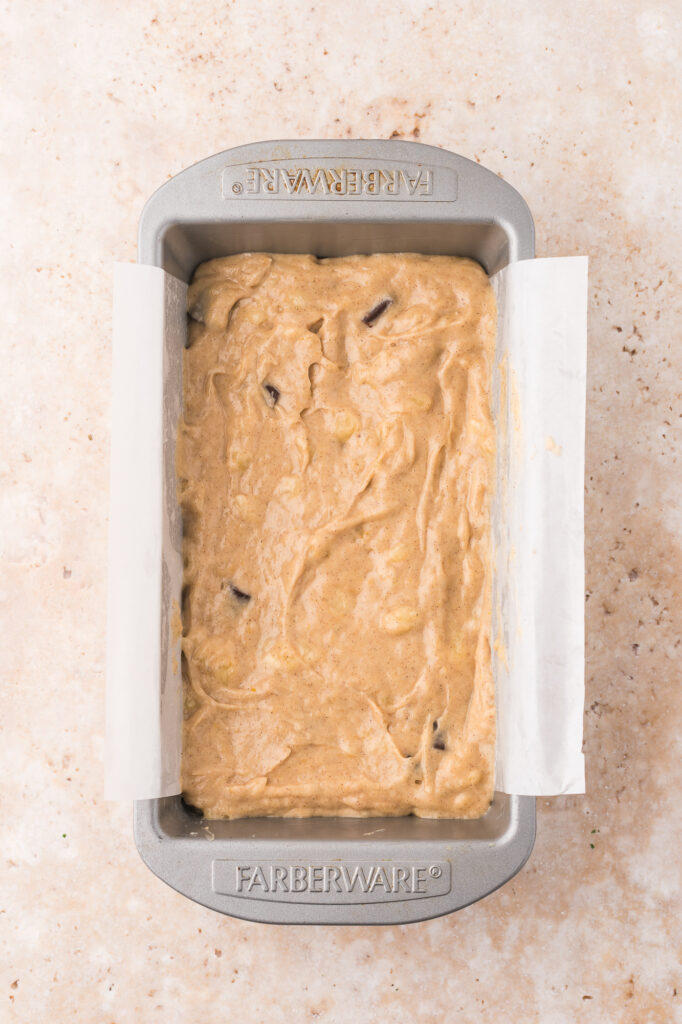 A loaf pan filled with batter for Chocolate Chunk Banana Bread.