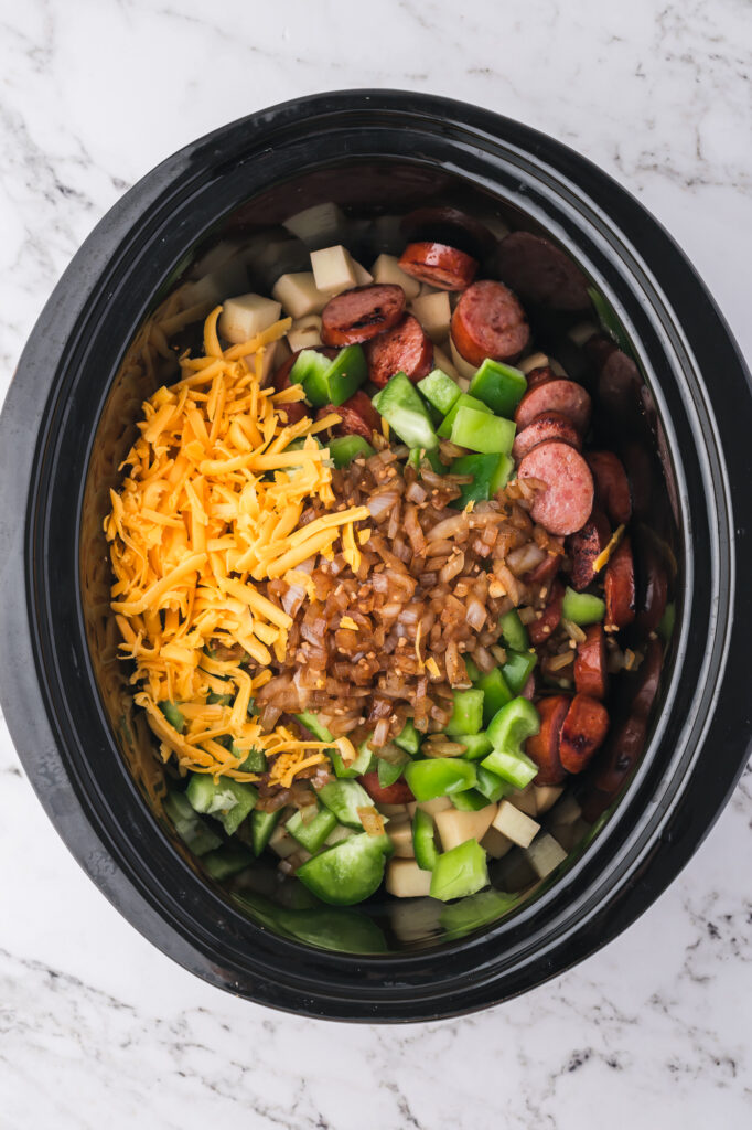 All the ingredients for Slow Cooker Sausage Potato Casserole in the slow cooker except for the sauce.