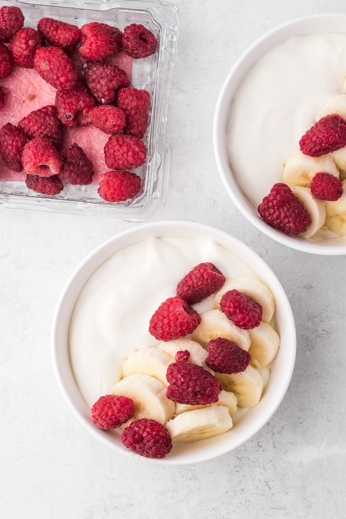 Two Whipped Cottage Cheese Bowls topped with bananas and raspberries.