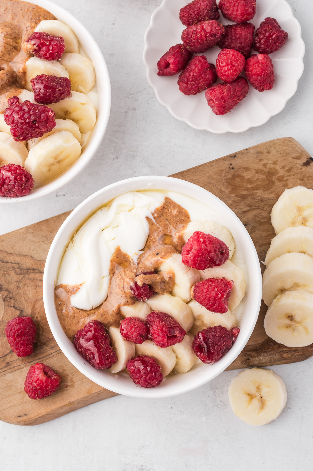 Two Whipped Cottage Cheese Bowls topped with bananas, raspberries, and almond butter.