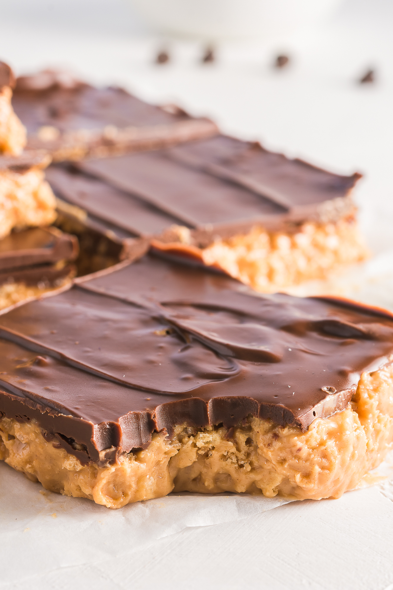 A close up of Crispy Peanut Butter Chocolate Bars and one of them has a bite in it.