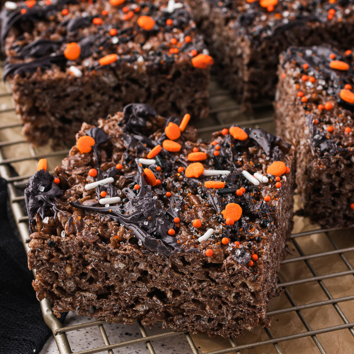 Sliced Spooky Cocoa Pebbles Treats on a cooling rack.