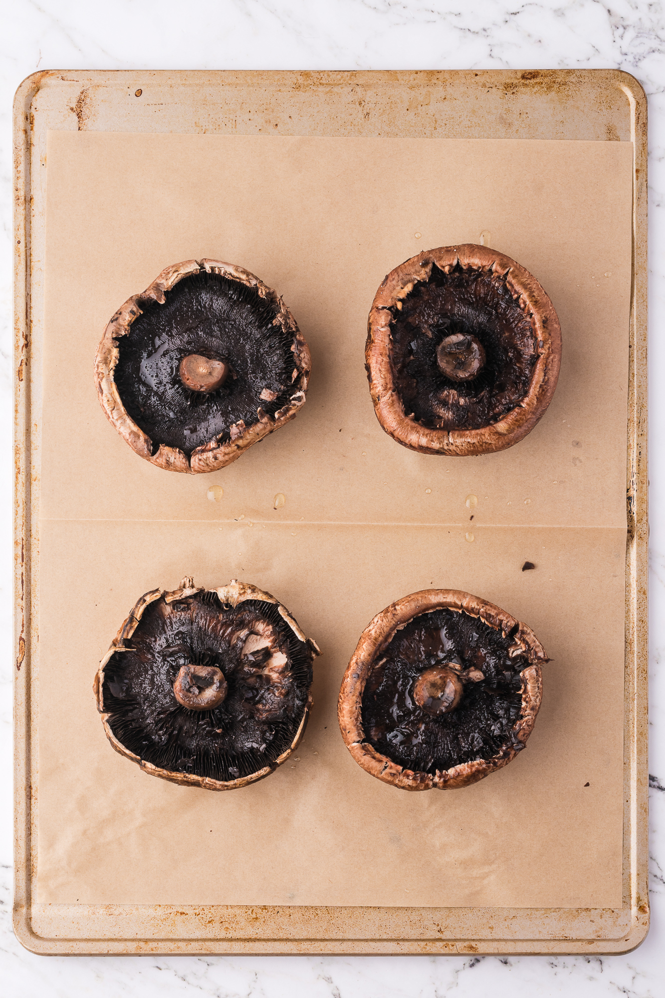 Four portobello mushrooms on a cutting board.