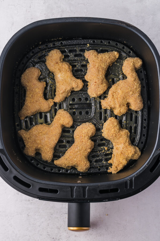 The raw breaded Air Fryer Dino Chicken Nuggets in the basket of the air fryer.