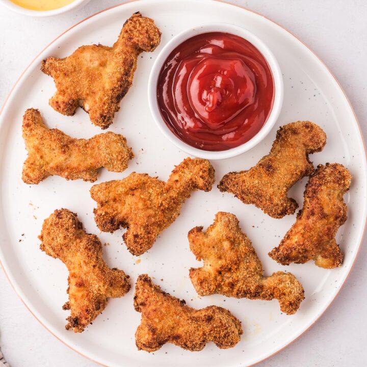 A plate of Air Fryer Dino Chicken Nuggets with a small bowl of ketchup.