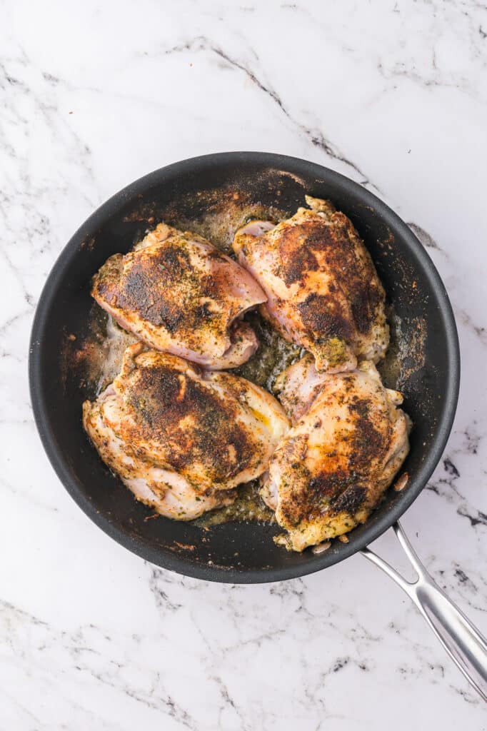 Four seared seasoned and floured chicken breasts.