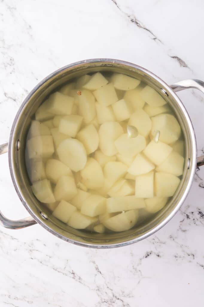 A pot of cubed potatoes covered in water.