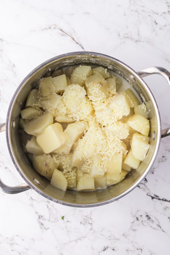 A pot of drain, cooked potatoes with butter, cream, and parmesan cheese.