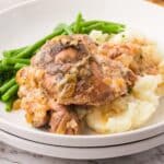 A plate of Slow Cooker Ranch Chicken with mashed potatoes and green beans.