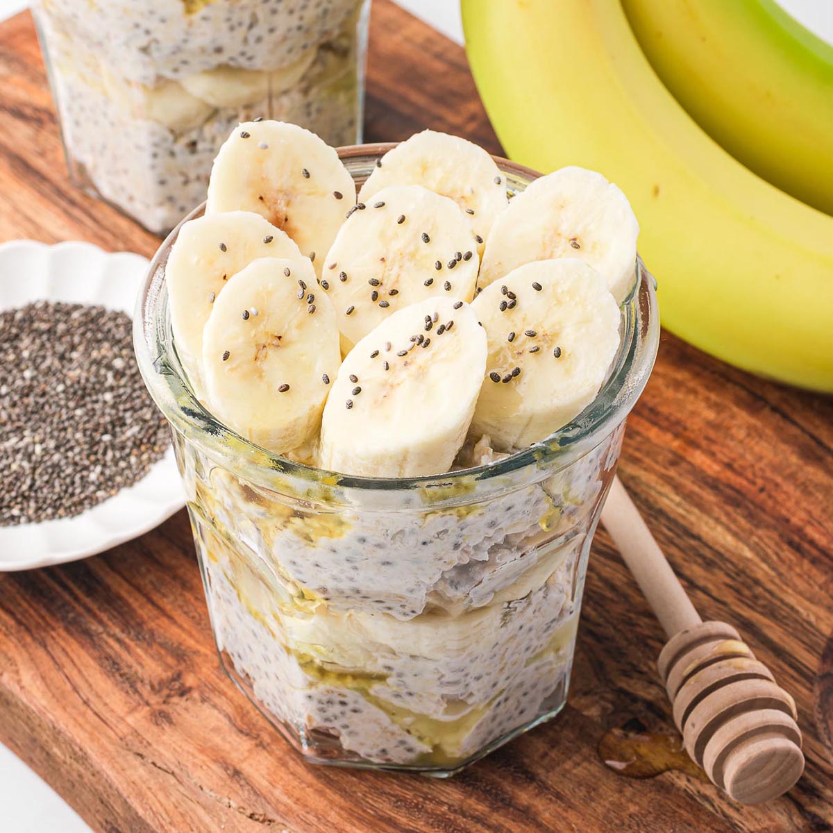 A jar of Banana Chia Overnight Oats on a wooden cutting board.